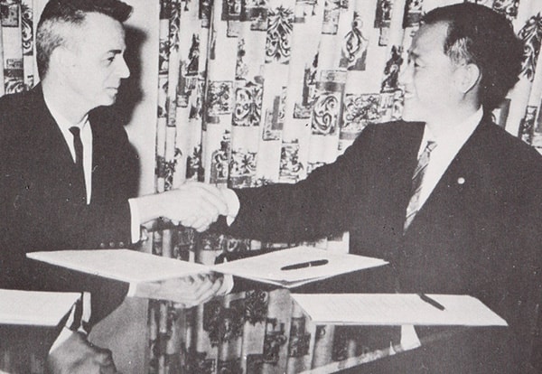 技術提携の調印を終え握手を交わす三科健次郎とミルナー社長（写真上）